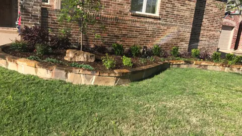 Chopped stone raised bed along a home foundation with new plantings