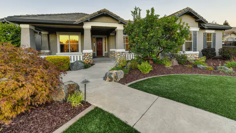 Front yard beds with fresh mulch beside a curved concrete walkway
