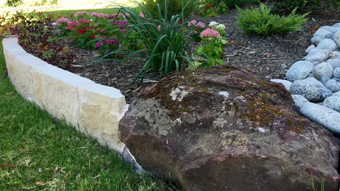 Limestone border with a large boulder accent and mulched bed