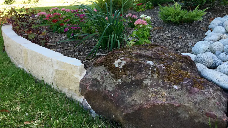 Cream limestone bed border with a boulder accent and mulched planting