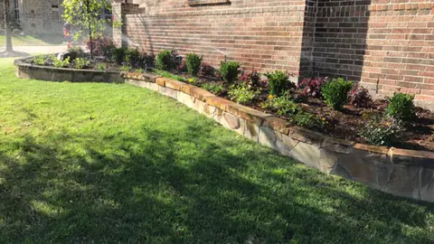 Newly installed stone-edged foundation bed with fresh plantings