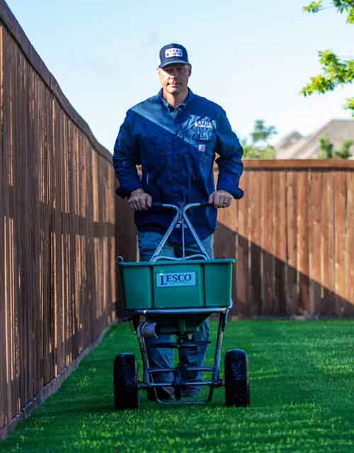 ryno pushing lesco cart for weed prevention and lawn care in flower mound tx